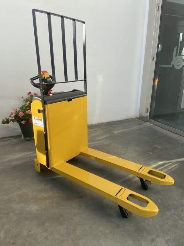 Transpaleta eléctrica amarilla con protección trasera y ruedas en interior.