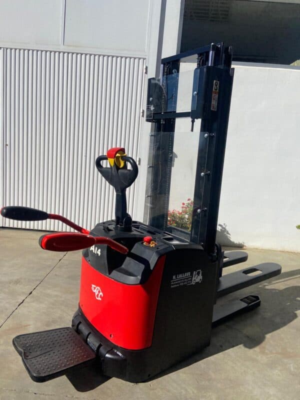 Apilador eléctrico de 1400kg en exteriores con horquillas largas y control ergonómico.
