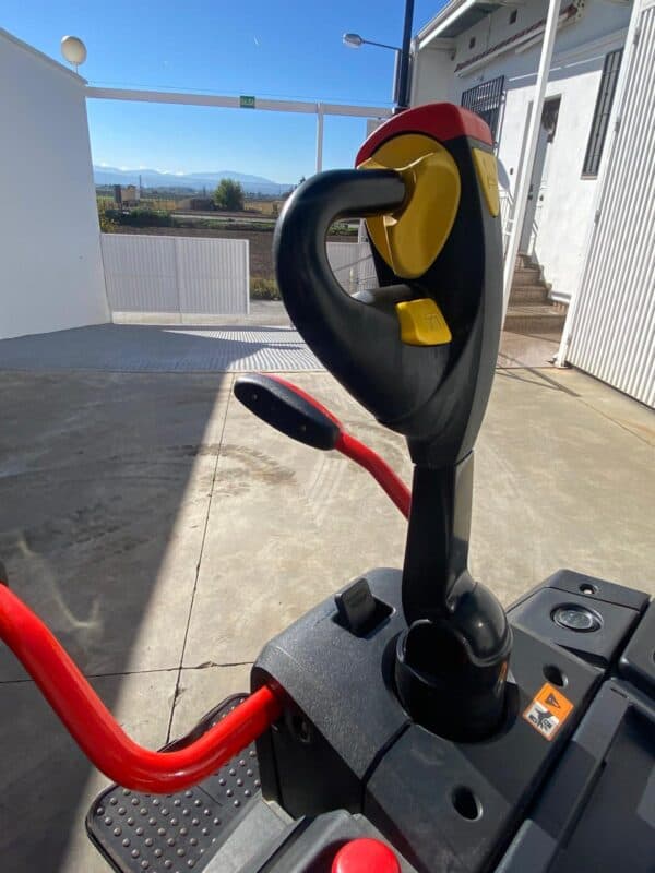Mango de apilador eléctrico con control ergonómico y vista del entorno exterior.
